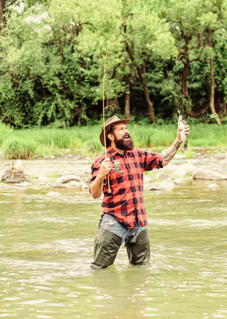 Trendy Hobby Store. bearded fisher in water. mature man fly fishing. man catching fish. fisherman show fishing technique use rod. summer weekend. Happy fly fishing. hobby and sport activityの写真素材