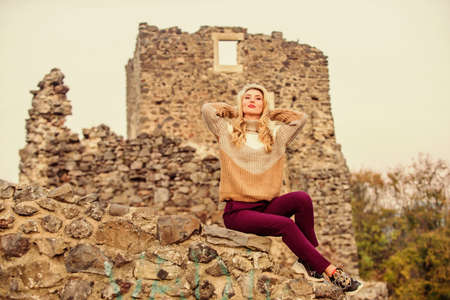 Woman makeup face sit on stony ruins background defocused. Tourism concept. Explore midcentury castle ruins. Fashionable girl tourist. Vacation and travel. Travel agency. Travel destinationsの写真素材