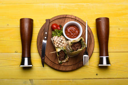 Minced meat wrapped with lavash bread on yellow wooden backgroundの写真素材