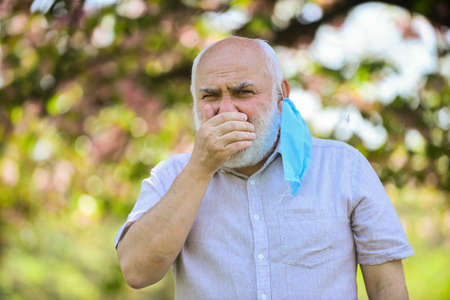 coughing man in respirator mask. spring blossom tree in park. coronavirus covid19. spring enjoyment. restricted public park. park is closed for quarantine due to coronavirusの写真素材