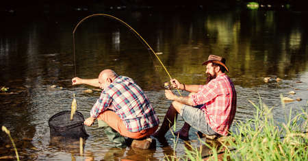 Black market caviar. Poachers fishing. Trap for fish. Men sit at riverside with fishing equipment. Illegal hunting caviar. Extracts eggs from sturgeon caught river. Poaching crime and fishing licenseの写真素材