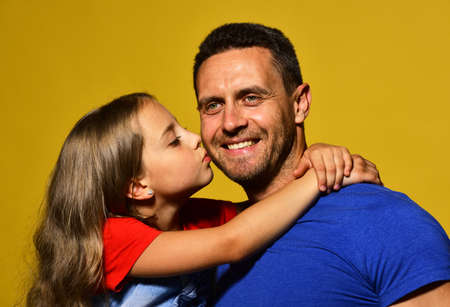 Daughter kisses her daddy in cheek. Child and father hug
