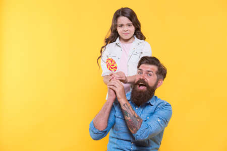 Give it to me. Unhappy child take candy from fathers hands. Candy shop. Lollipop or sucker on stick. Sugary treat. Candy factory and confectionary. Twist you cant resist, copy spaceの写真素材