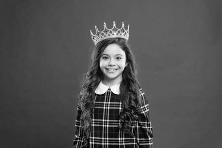 Every girl dreaming to become princess. Lady little princess. Girl wear crown red background. Monarch family concept. Princess manners. Monarch attribute. Kid wear golden crown symbol of princessの写真素材