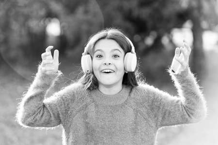 Listen in style. Little girl child wearing headphones. Happy child enjoy listening to music on the go. Adorable little girl outdoor. All she wants to hear is musicの写真素材
