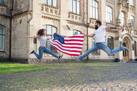 Explore USA. Vacation and travel. Independence day. National holiday. Bearded hipster and girl jumping. 4th of July. American tradition. American patriotic people. American couple USA flag outdoorsの写真素材