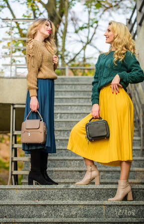 Good mood at any weather. girl friends go upstairs. fall season color trends. Pleated trend. girls in corrugated skirt and sweater. female beauty. knitwear fashion. stylish autumn women outdoorの写真素材