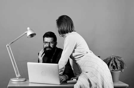 business couple at computer. woman and man work in office at laptop. businessman and assistant solve problem. secretary with boss at workplace. sexual harassment. data and information. Quick briefingの写真素材