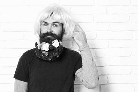 hipster with flowers in beard on white brick wall background