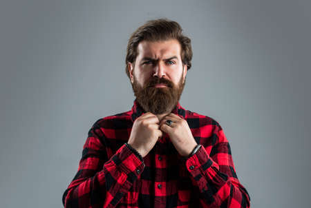Bearded man fastens his shirt.. Hair and beard care. Confident and handsome brutal man.の写真素材