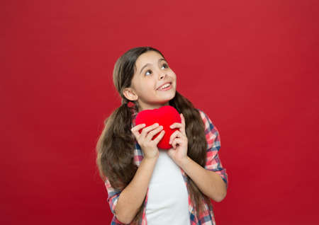Little girl holding red heart. Having heart problem and heartache.の写真素材
