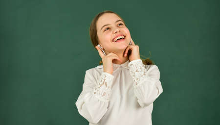 Listening audio book. Student girl in headphones at chalkboard background copy space. Audio translation. Audio learning concept. Homeschooling online education. Girl in earphones listening to musicの写真素材