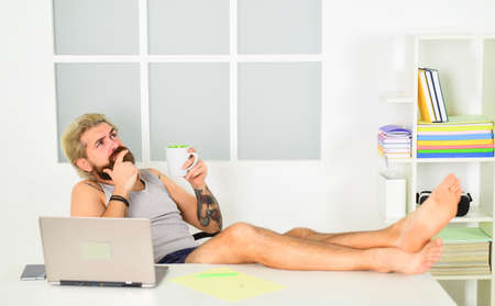 working with comfort. self education online. stay at home. lock down on coronavirus quarantine. distant business. barefoot businessman at laptop in home office. bearded man think and drink coffeeの写真素材