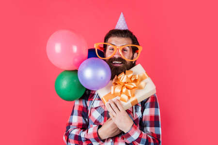 Having fun. funny man in birthday hat. happy holiday celebration. party goer going crazy. having fun with balloons. prepare for anniversary. event manager with gift box. brutal male on partyの写真素材