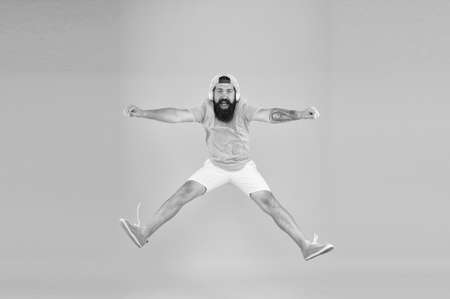 bearded man listen music. happy guy wear headphones. summer vacation party. brutal hipster jump high. his favorite song. mature dj full of energy. feel freedom. celebrating successの写真素材