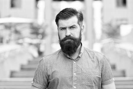 Walking down the street. Mature hipster with beard on stairs. Bearded man. Confident brutal man walk street. Male barber care. Male fashion. Guy with beard and mustache. Barber salon. Street styleの写真素材