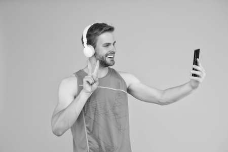Application for trainings with online couch. Repeat after video. Athletic man listen music smartphone. Workout playlist. Sport and fitness. Health and wellness. Workout motivation. Tracking progressの写真素材