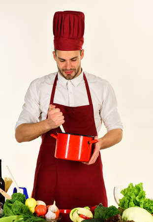 Cook works in kitchen near table with vegetables and tools.