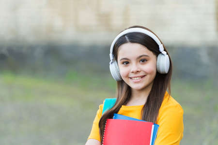 Modern child girl with headphones back to school hold textbook, modern approach conceptの写真素材