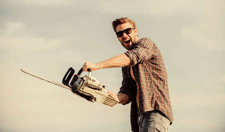 Sharp blade. Dangerous job. Feeling manly. Powerful chainsaw. Handsome man with chainsaw blue sky...