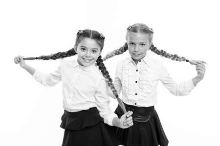 Schoolgirls wear formal school uniform. Sisters little girls with braids ready for school. School fashion concept. Be bright. School friendship. Sisterhood relationship and soulmates. On same waveの写真素材