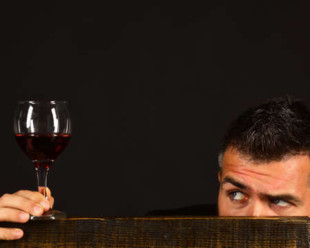 Degustator with hidden face behind wooden chair. Sommelier tastes drink