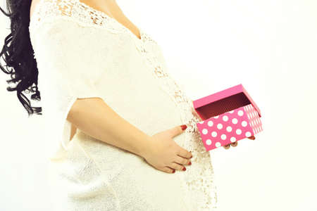 female hands of pregnant woman holding pink present boxの写真素材