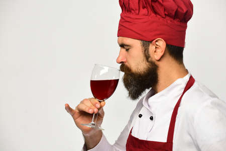 Cook with serious face in burgundy uniform drinks alcohol.の写真素材