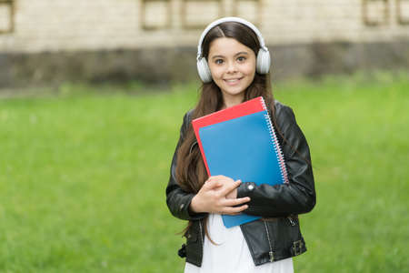 Girl listening audio carry textbooks on way to school, language lessons conceptの写真素材