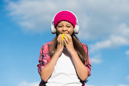 Healthy food choice. Little kid eat apple on sunny blue sky. Tooth-friendly food. Dental diet. Vitamin snack. Dental health. Oral hygiene. Dental care habits. Preventing caries. Pediatric dentistryの写真素材