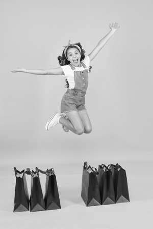 happy jump. online shopping for kids. give-away concept. ready for holiday celebration. little girl after successful shopping. happy childhood. child with package bags. buy presents on cyber mondayの写真素材