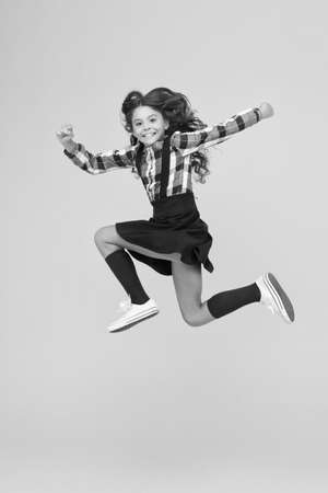 Be happy everyday. Happy child in midair yellow background. Having fun. Happy childhood. Raising happy kid. School holidays. International childrens dayの写真素材