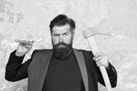 Real blade. Brutal methods. old weapon. Barbershop hairstyle. Brutal barber. Daring barber concept. Man hipster with axe. Sharp ax and straight razor. Masculinity and brutality. Vintage barbershopの写真素材