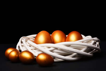 traditional eggs painted in golden color inside woven wooden wreathの写真素材