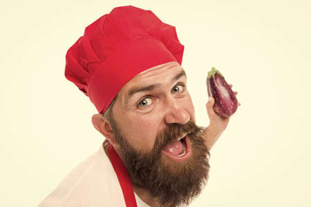 Vegetarian recipe. Chef holds eggplant. Cook in uniform holds vegetables. Eat fresh food. Vegetarian chef cooking food. Vegetarian restaurant. Healthy cooking concept. Man with beard white backgroundの写真素材