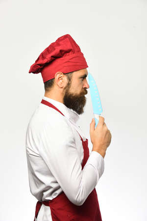Chef holds sharp blue knife, side view. Man with beardの写真素材