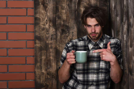 handsome guy holding cup on brick wall and wooden backgroundの写真素材