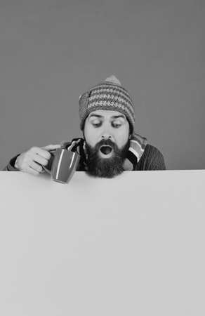 Hipster with beard and shocked face has tea or coffee.の写真素材