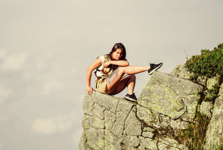 On edge of world. Woman sit on edge of cliff in high mountains blue sky background. Hiking peaceful moment. Enjoy the view. Extreme concept. Tourist hiker girl relaxing edge cliff. Dangerous relaxの写真素材
