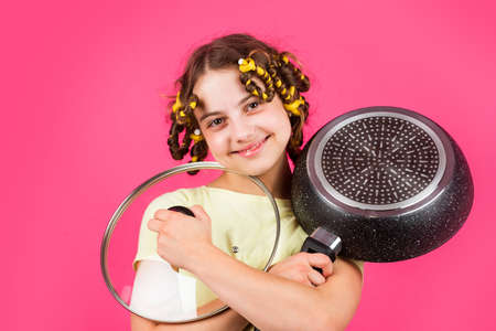 Perfect for pancakes. Small girl with curlers in hair. Pin up style. Culinary and house duties. Girl hold Frying Pan. Little kid hold pan cooking meal. Home utensils. Kitchen accessory. Healthy foodの写真素材