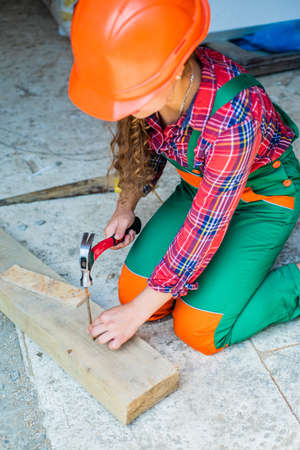 working with wood in a garage. happy childhood. hardworking child hammering nail. teenage girl with hammer. little girl working with wood. kid in carpentryの写真素材