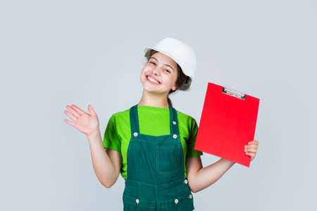 builder in helmet smiling in front of plan. future interior designer. child in hardhat holding...