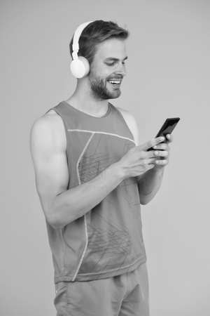 Mobile device is your workout companion. Happy sportsman hold mobile phone. Mobile fitness equipment. Innovative training solutions. Modern life. High tech products. Mobile gym to stay in shapeの写真素材
