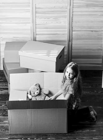 Happy childhood. Relocating family stressful for kids. Kid girl relocating boxes background. Relocating concept. Delivery service. Box package and storage. Small child prepare toys for relocationの写真素材