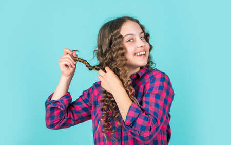 Enjoying shiny curls. Balm oil conditioner for styling. Hairdresser supplies. Fashion and beauty. Small girl hairdresser salon. Little child curly hair. Hairstyle for party. Beautiful Healthy hairの写真素材