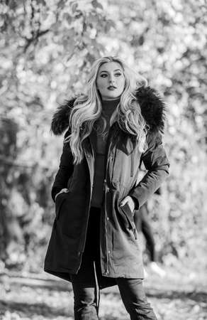 Modern outfit for youth. Girl in warm coat stand in park nature background defocused. Create fall outfit to feel comfortable and pretty. Woman long blonde hair wear stylish outfit with parkaの写真素材