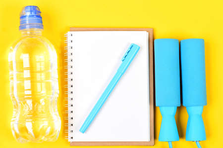 Notepad, pen and gym equipment top view on yellow backgroundの写真素材