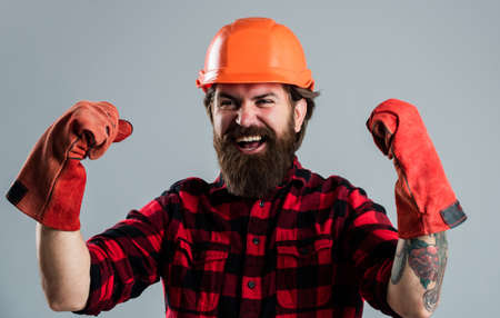 celebrating success. man in gloves. construction worker in hard hat. engineer architect working in safety helmet. brutal technician builder. factory worker mechanic. industrial worker in helmetの写真素材