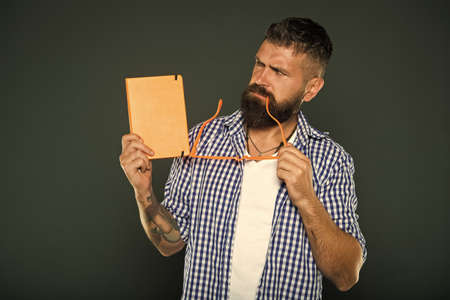 Being absorbed in thinking. University male student holding lecture notes. Bearded man with party glasses and lesson book. Study nerd with book. Book nerd holding fancy glassesの写真素材