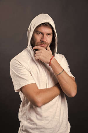 Man in hood touch beard. Bearded man with thinking face in casual sweatshirt. Fashion model wear...